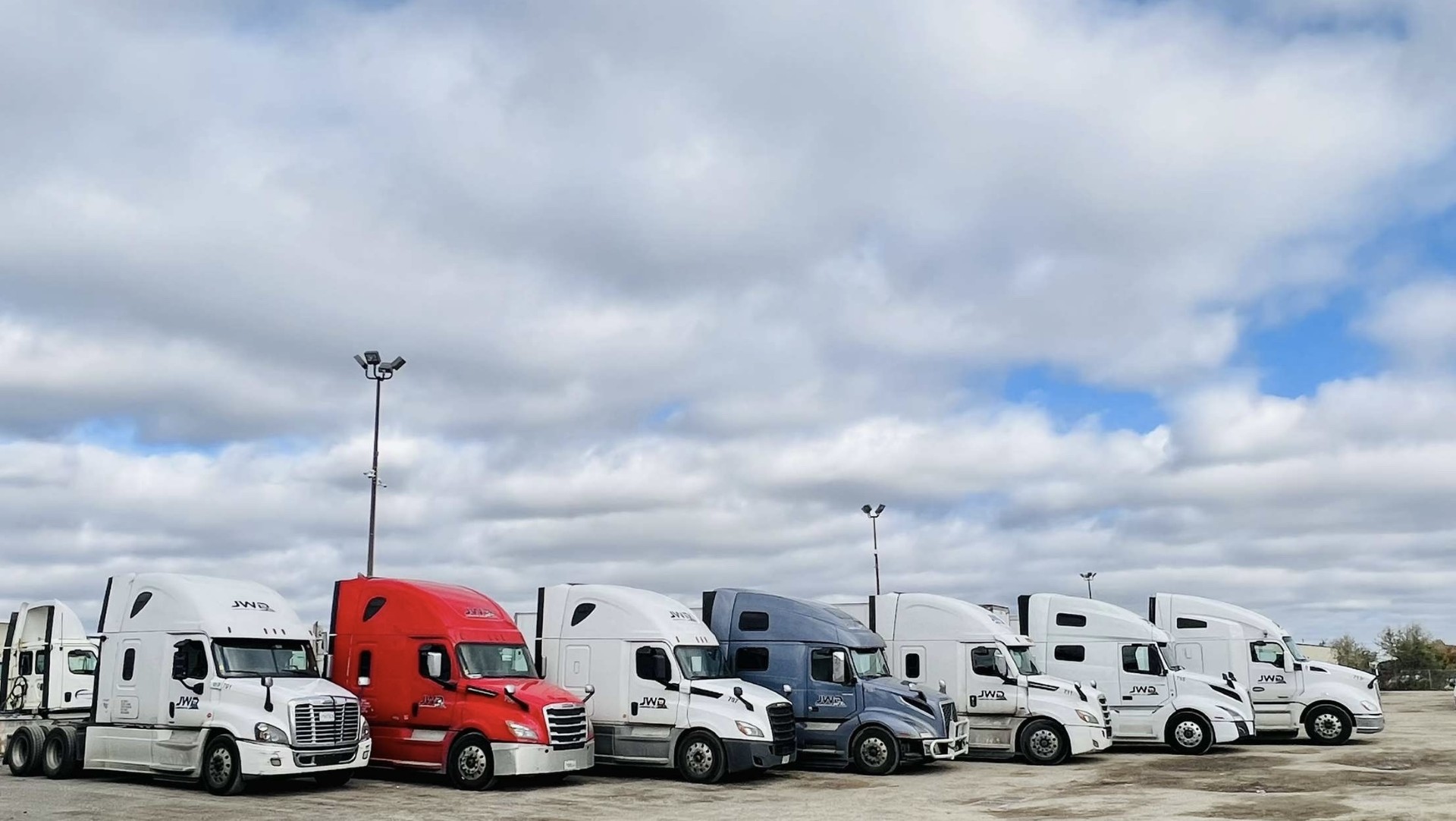 Seven JWD Logistics tractors lined up at the terminal yard.